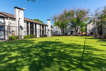 A sunny day at the park with a building in the background.